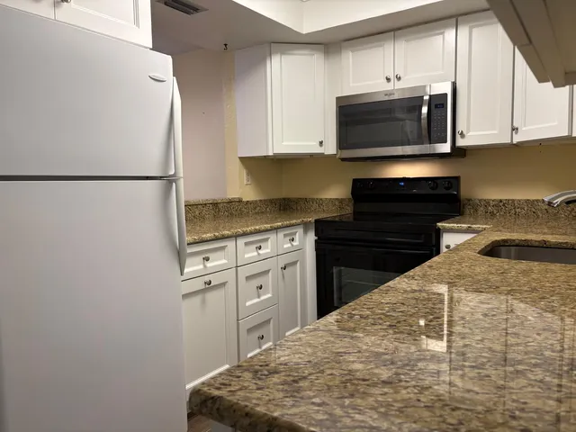 a kitchen with kitchen island a sink a stove a microwave and cabinets