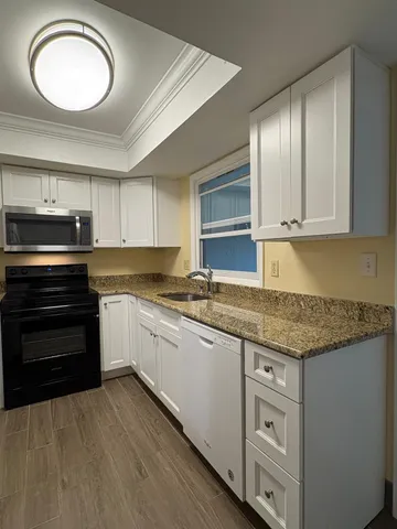 a kitchen with granite countertop a stove cabinets and microwave