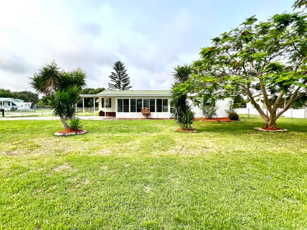 a view of a house with a big yard and palm trees