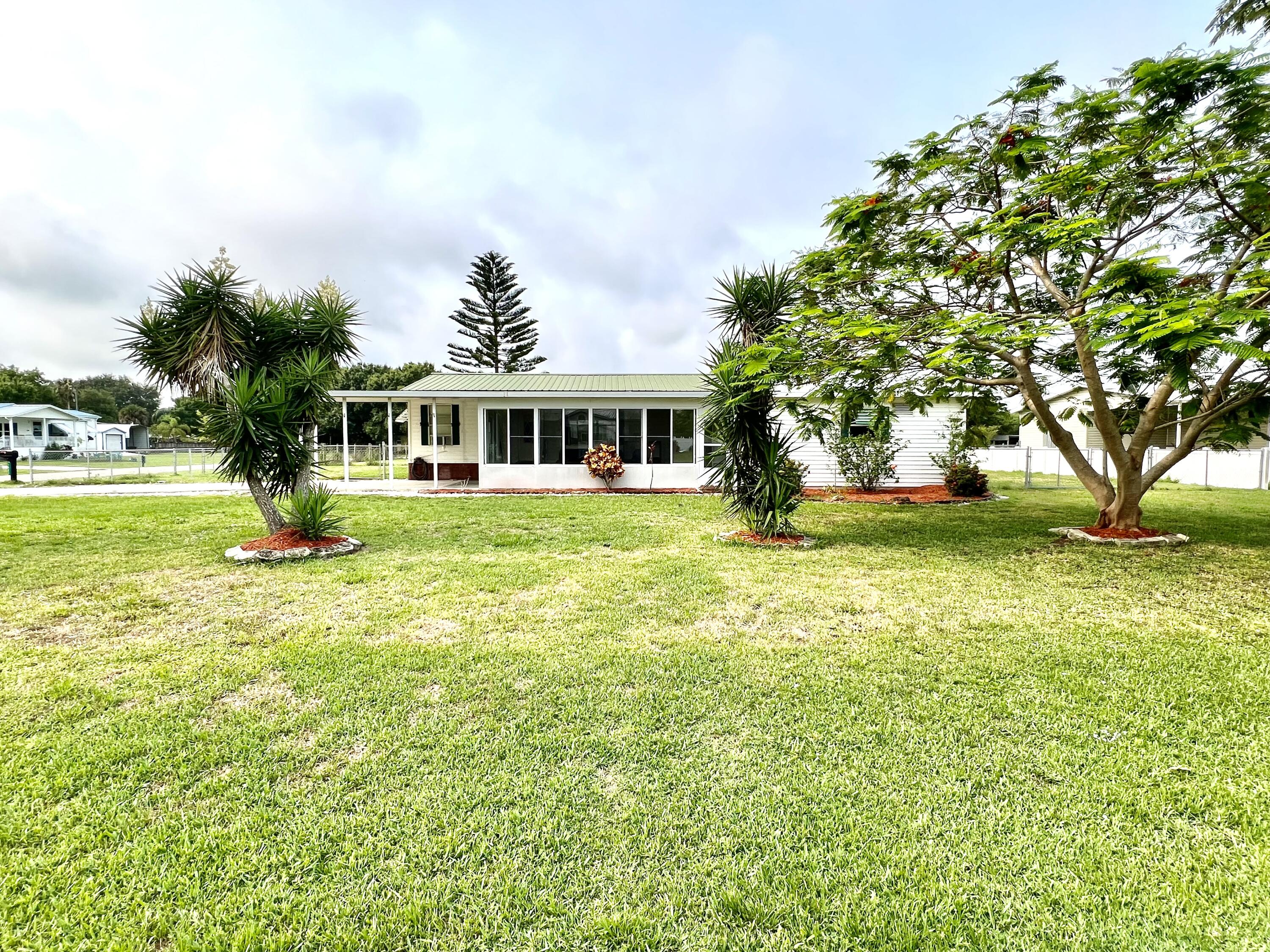 1303 Jordan Loop Okeechobee, FL 34974 - Photo 8 of 33 a view of a house with a big yard and palm trees