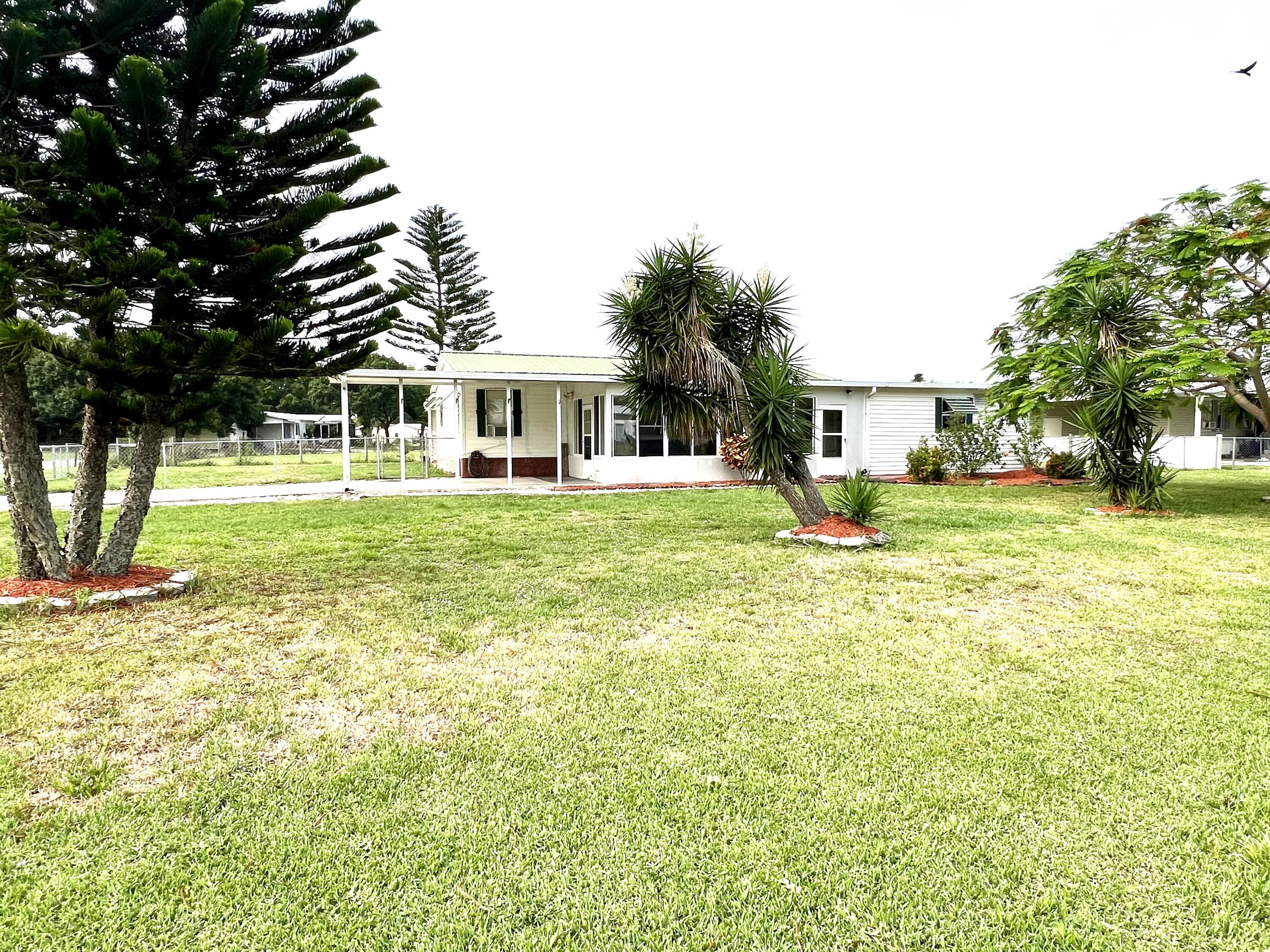 1303 Jordan Loop Okeechobee, FL 34974 - Photo 9 of 33 a view of a house with a big yard and large trees
