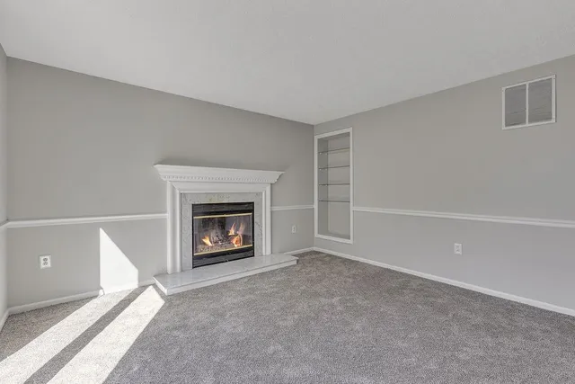 a view of an empty room with a fireplace and a window