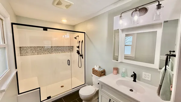 a bathroom with a shower sink vanity mirror and toilet