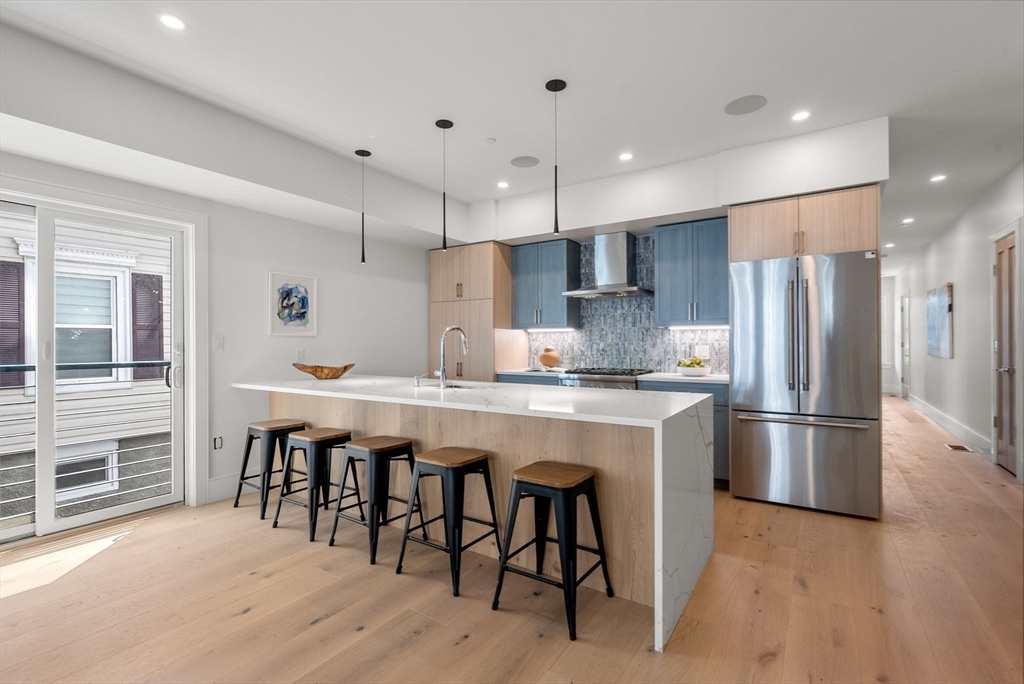 527 East 7th Street, Unit 1 Boston, MA 02127 - Photo 5 of 24 a kitchen with stainless steel appliances granite countertop a refrigerator a stove a sink dishwasher a dining table and chairs with wooden floor