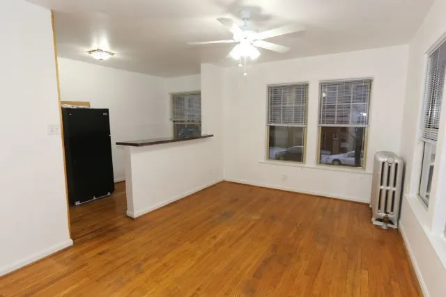 a view of empty room with wooden floor and fan