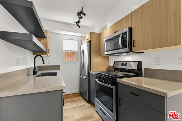 a kitchen with stainless steel appliances a stove sink microwave and refrigerator