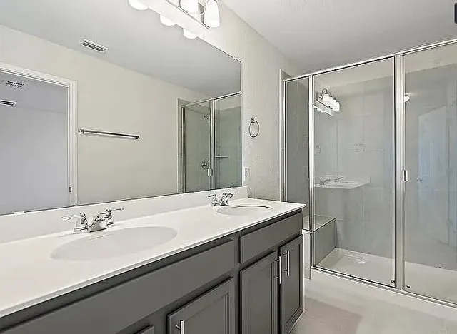 a bathroom with a sink double vanity granite tub and shower