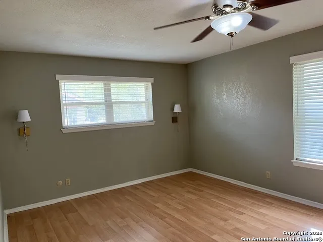a view of empty room with wooden floor and fan