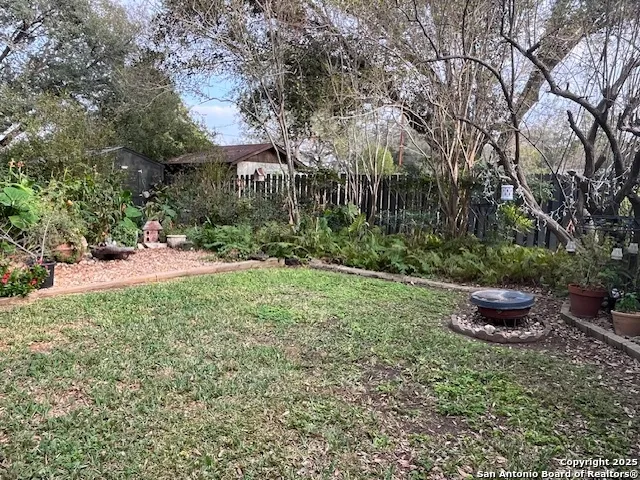 a view of a backyard with table and chairs potted plants and tree