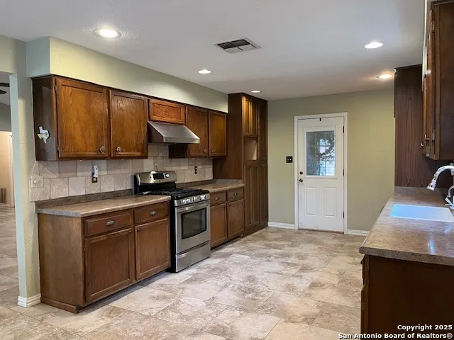 a kitchen with stainless steel appliances granite countertop a stove refrigerator sink and microwave
