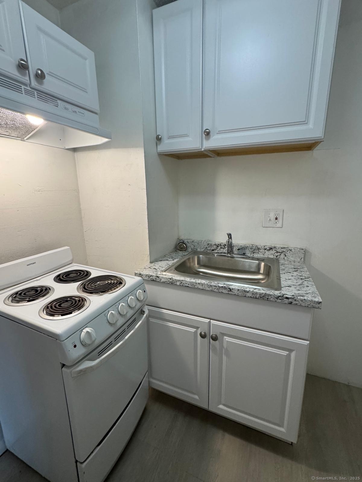 a kitchen with granite countertop cabinets sink and stove