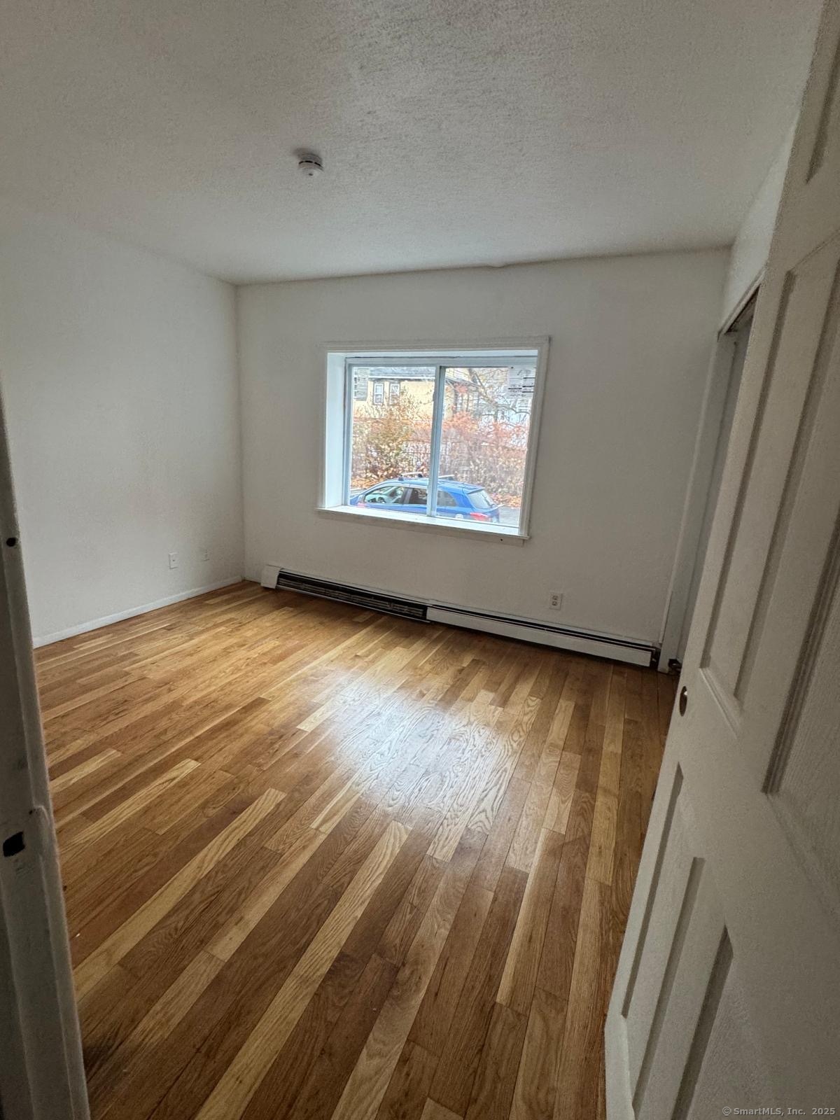 404 Charles Street, Unit C4 Bridgeport, CT 06606 - Photo 3 of 3 a view of an empty room with wooden floor and a window