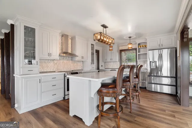 a kitchen with stainless steel appliances a dining table chairs and wooden floor