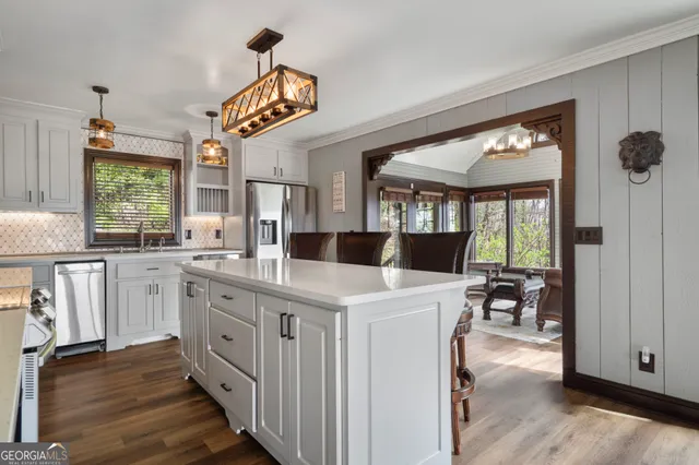 a kitchen with kitchen island a large counter top space appliances and a window
