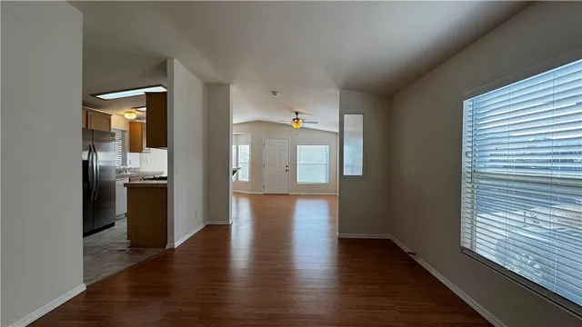 a view of a hallway with wooden floor and a kitchen