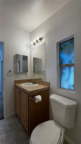 a bathroom with a granite countertop toilet sink and mirror