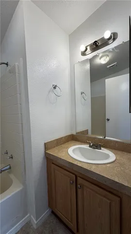 a bathroom with a granite countertop sink a mirror and a bathtub