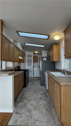 a large kitchen with a large counter top space a sink stainless steel appliances and cabinets