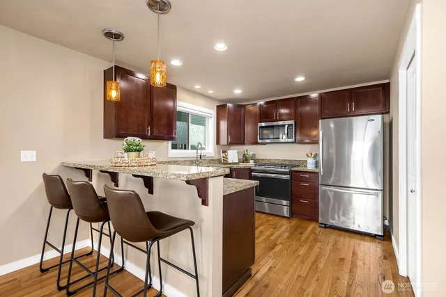 a kitchen with kitchen island granite countertop wooden floors and stainless steel appliances