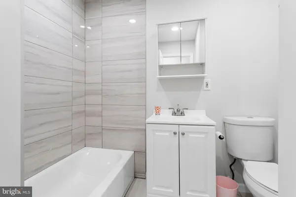 a white bath tub sitting next to a white sink and vanity