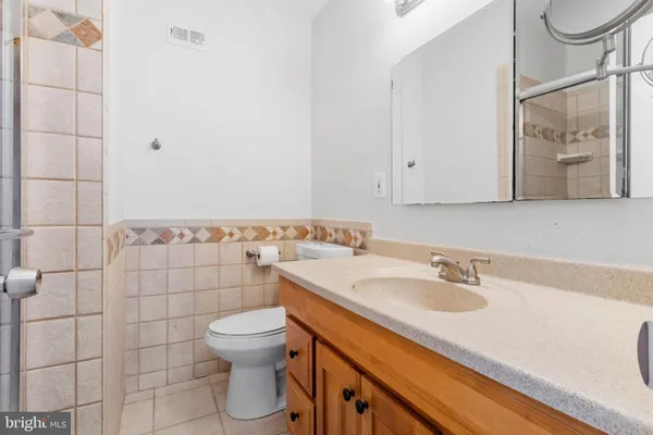 a bathroom with a granite countertop sink a mirror and shower