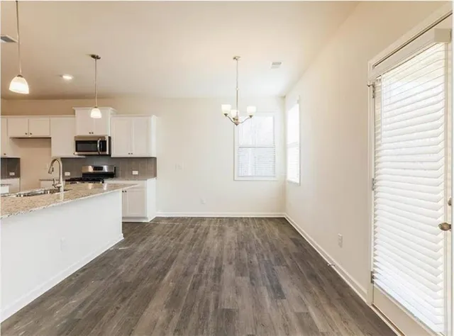 a kitchen with granite countertop a stove a sink and white cabinets with wooden floor