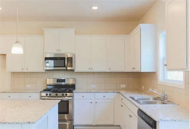 a kitchen with stainless steel appliances granite countertop a sink a stove and a microwave