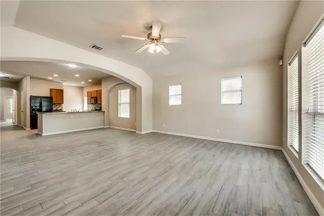 a view of an empty room with wooden floor and a kitchen
