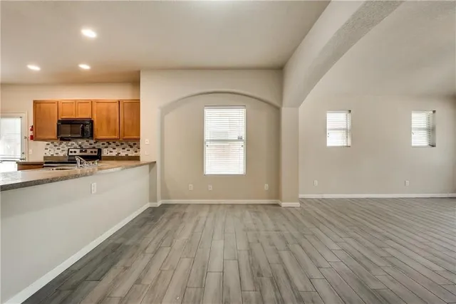 an empty room with wooden floor and stainless steel appliances