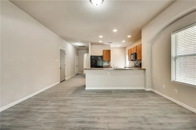 a view of kitchen with kitchen island stainless steel appliances wooden cabinets and window