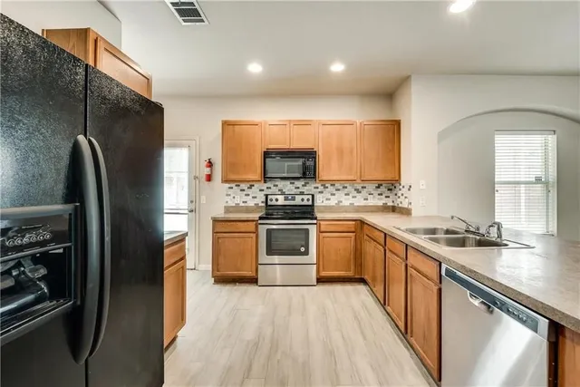 a kitchen with stainless steel appliances a stove a sink and a refrigerator