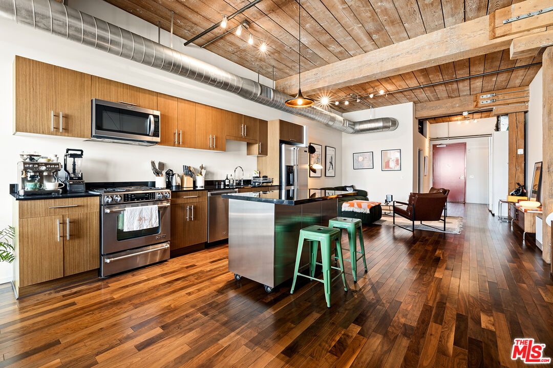 530 South Hewitt Street, Unit 425 Los Angeles, CA 90013 - Photo 3 of 22 a kitchen with stainless steel appliances granite countertop a stove a refrigerator a kitchen island a dining table and chairs with wooden floor