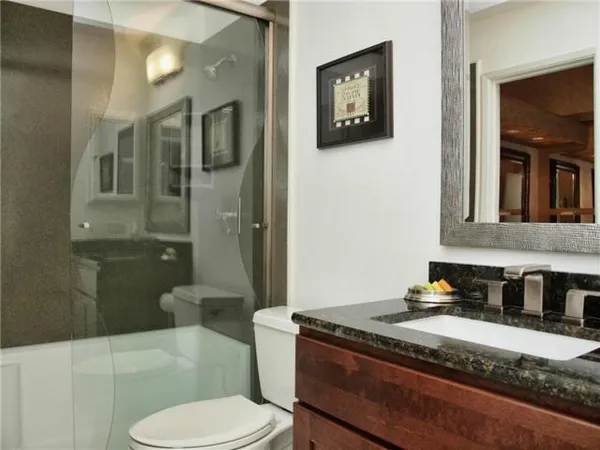 a bathroom with a granite countertop sink mirror vanity and toilet