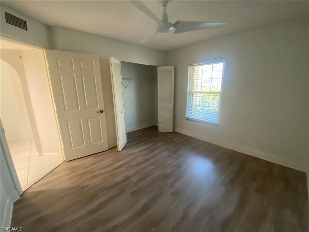 705 Augusta Boulevard, Unit 7055 Naples, FL 34113 - Photo 12 of 18 a view of an empty room with wooden floor and a window