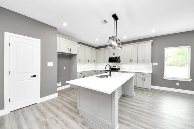 a large kitchen with kitchen island a sink a center island stainless steel appliances and cabinets