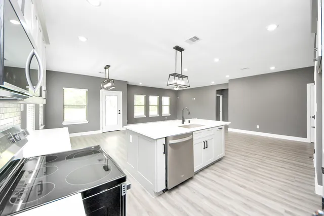 a large white kitchen with wooden floor