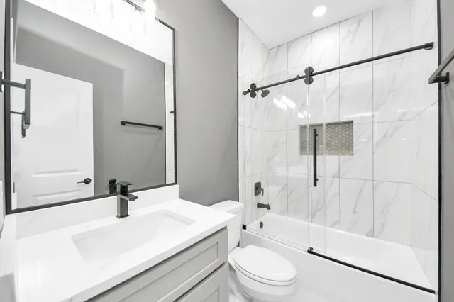 a bathroom with a sink a toilet a mirror and shower