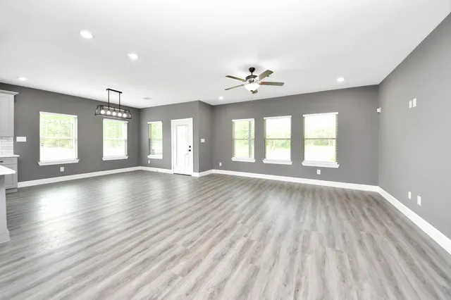 a view of an empty room with a window and wooden floor