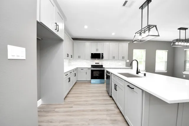 a large kitchen with stainless steel appliances kitchen island granite countertop a sink and cabinets