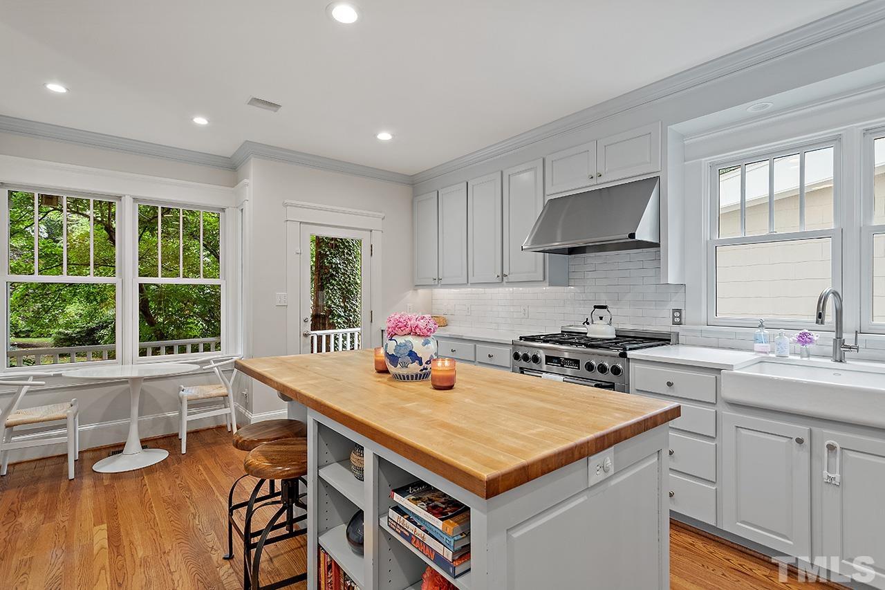 2001 McCarthy Street Raleigh, NC 27608 - Photo 23 of 43 a kitchen with a stove a sink a refrigerator and a dining table with wooden floor