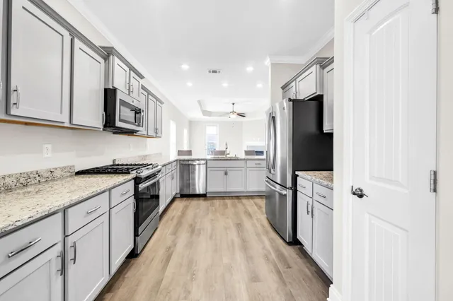 a large kitchen with stainless steel appliances granite countertop a stove a sink and a refrigerator