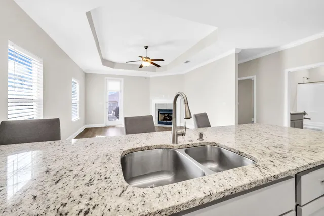 a kitchen with a sink granite counter tops and a view of living room