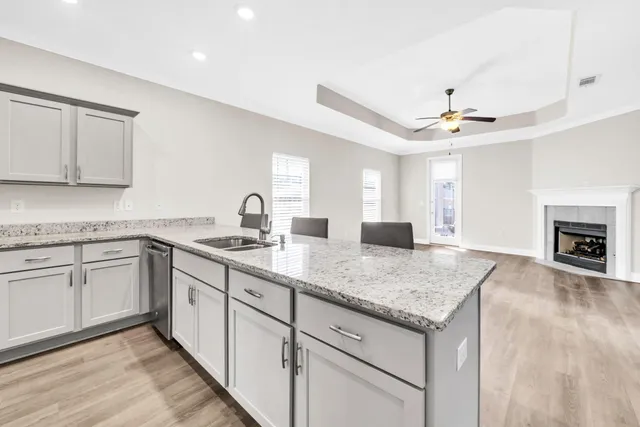 a kitchen with granite countertop a sink stainless steel appliances and white cabinets