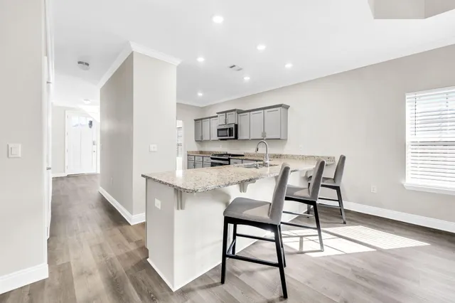 a kitchen with stainless steel appliances a dining table chairs and wooden floor