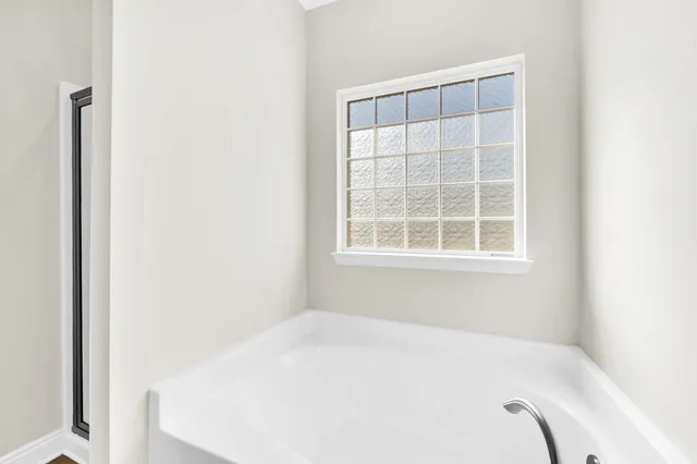 a white bed in a bathroom next to a window
