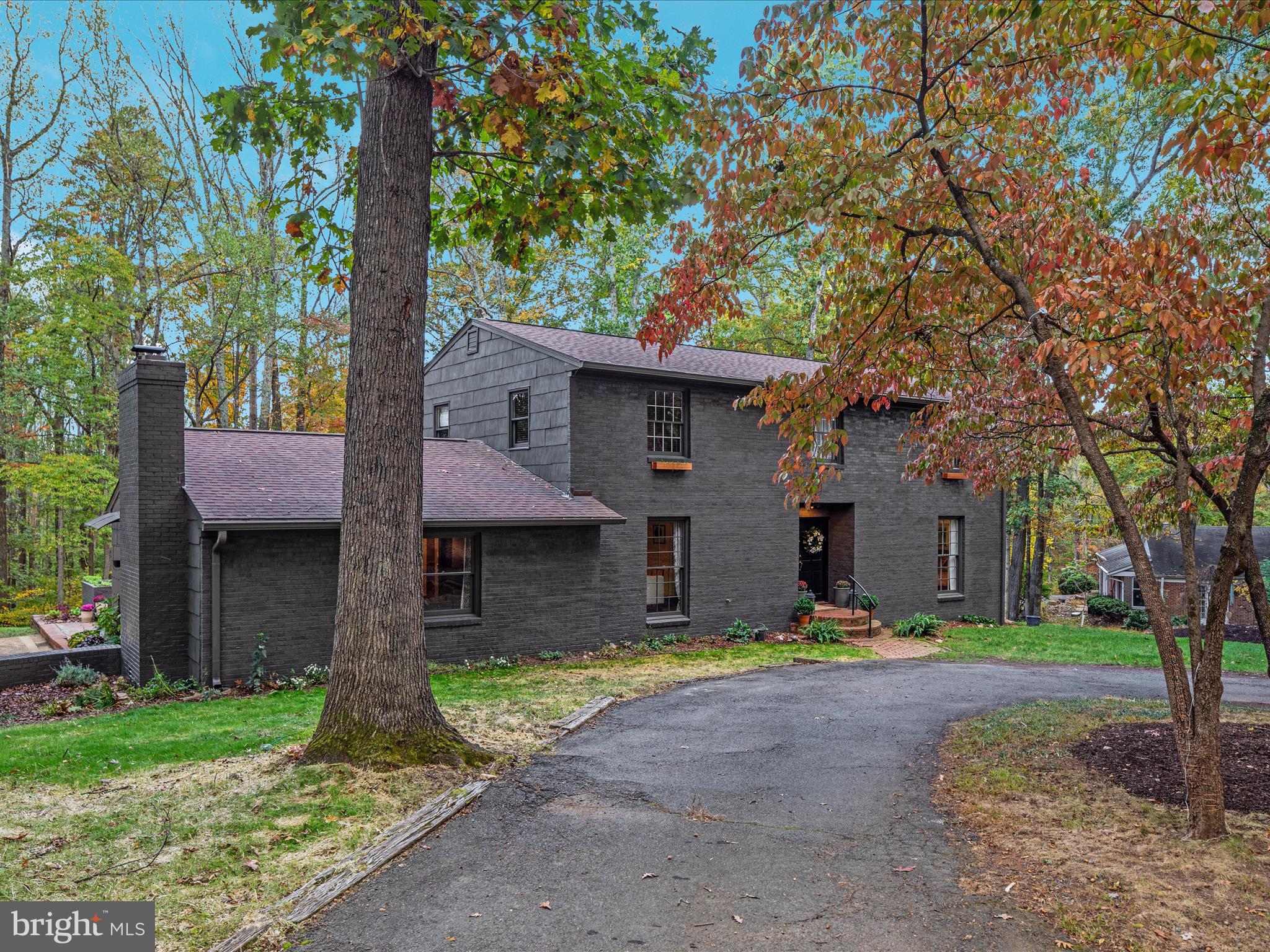 a front view of a house with a yard and large tree