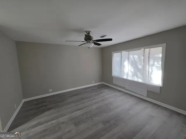 a view of an empty room with wooden floor and a window