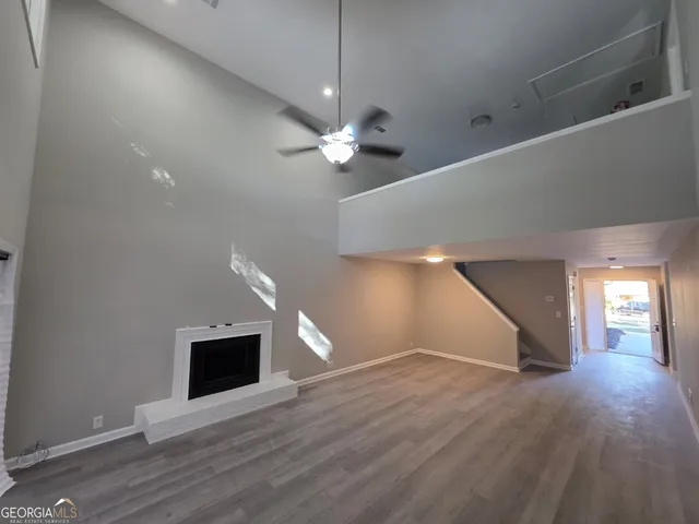 a view of an empty room with wooden floor and a ceiling fan