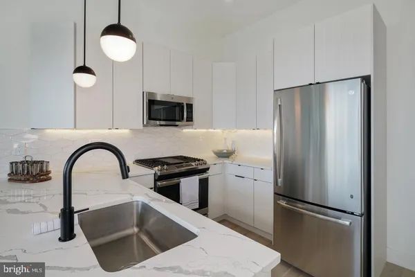 a kitchen with stainless steel appliances granite countertop a refrigerator a sink a stove and a kitchen island