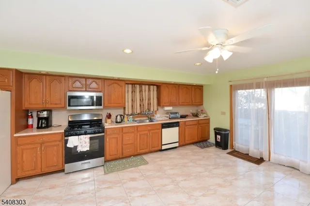 a large kitchen with stainless steel appliances granite countertop a stove refrigerator and a microwave oven